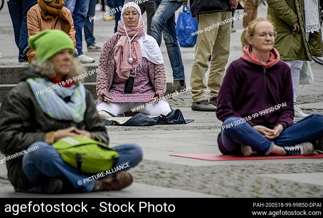 16 May 2020, Hamburg: Participants of a meditation demo at the Hamburg town hall market sit in lotus position on the stones
