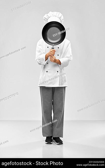 female chef peeking out from behind frying pan