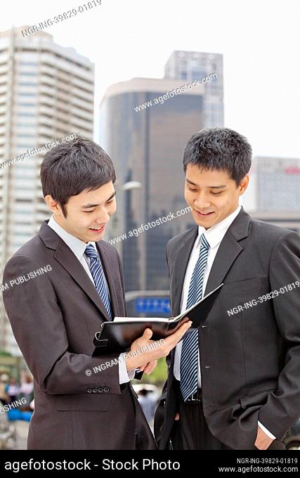 Two Businessmen Looking at Note Pad