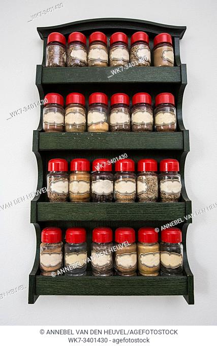 Jars of herbs and spices in wooden rack on white background, vintage design, close-up