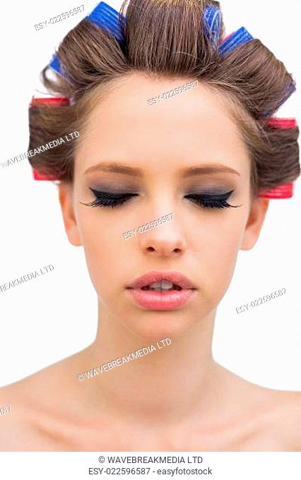 Pretty model with hair curlers closing eyes