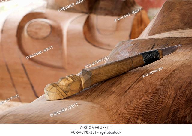 A carving tool rests atop a roughed in Totem Pole, Alert Bay