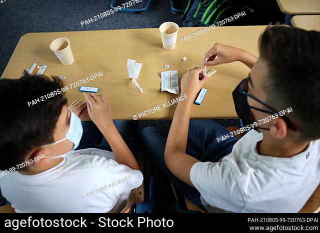 05 August 2021, Hamburg: Two pupils of class 6a at the Goethe-Gymnasium in Hamburg-Lurup do a Corona quick test in the classroom on the first school day after...