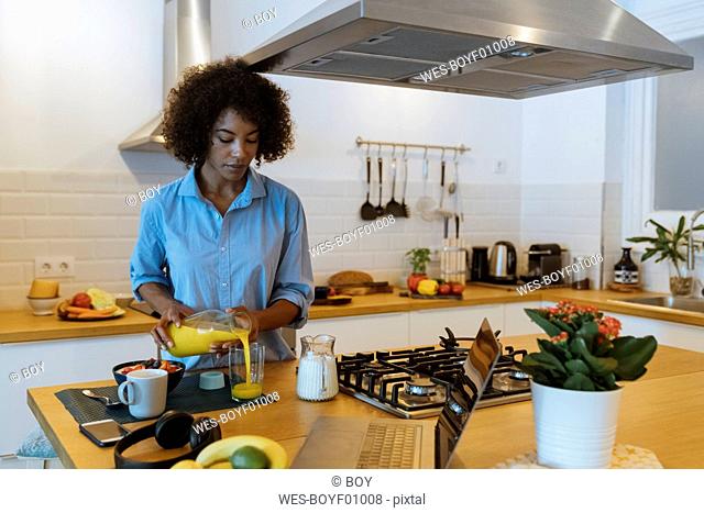 Woman having breakfast in her kitchen, drinking orange juice