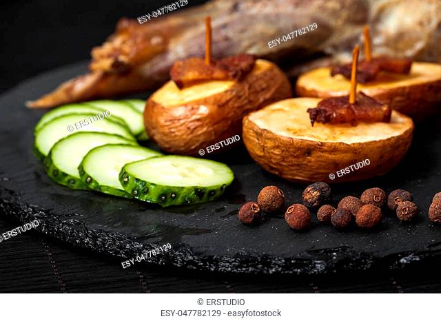 potato wedges, peas pepper and leg of lamb on black plate closeup