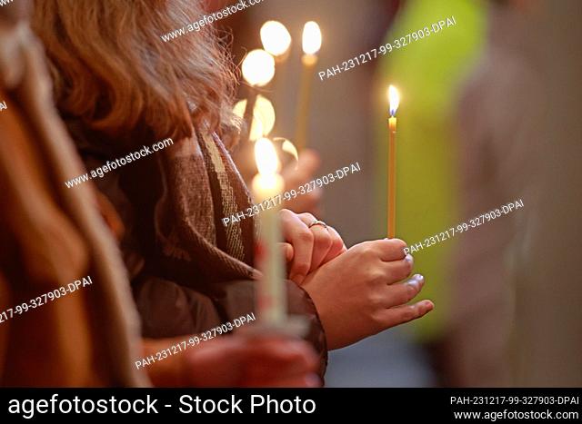 17 December 2023, Saxony-Anhalt, Halberstadt: Participants in an ecumenical service in St. Sixtus and St. Stephen's Cathedral hold candles symbolizing the Light...