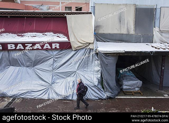 17 February 2021, Greece, Athen: A man walks past closed shops in Athens' main market. A strict lockdown has been in effect for the greater Athens area for a...