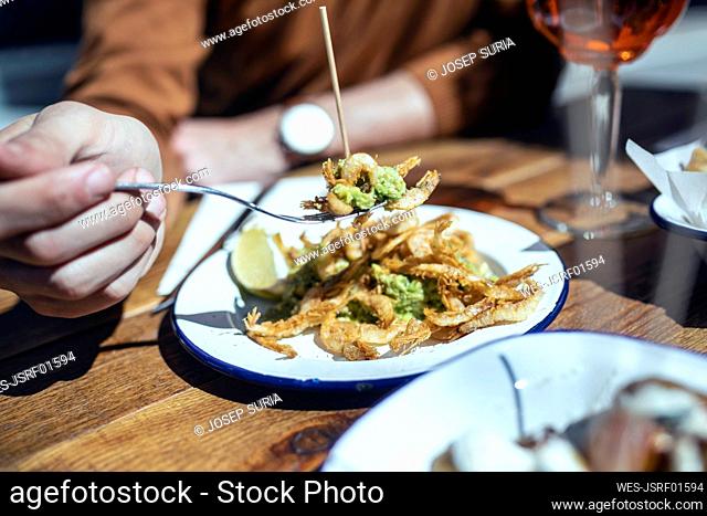 Mid adult man having fried prawns in restaurant