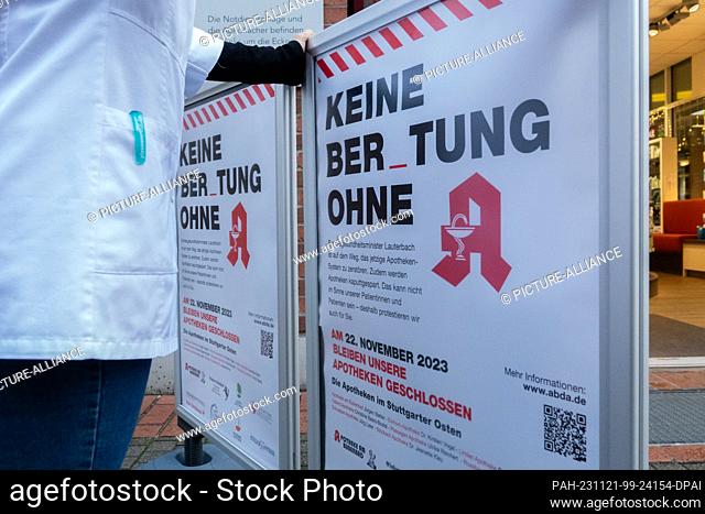 21 November 2023, Baden-Württemberg, Stuttgart: A pharmacist puts up a sign outside a pharmacy in Stuttgart. Pharmacies announce their one-day closure ahead of...