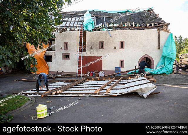 22 September 2023, Rhineland-Palatinate, Nusbaum: Carpenters work on the roof debris of a farm building that was damaged by a tornado the day before
