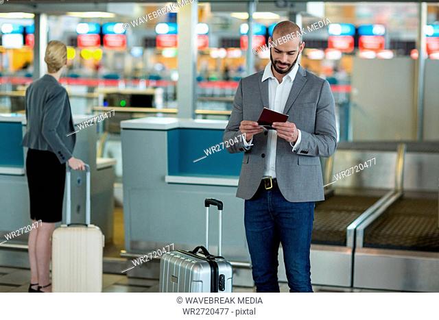 Businessman with luggage checking his boarding pass