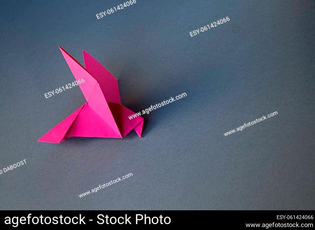 Pink paper dove origami isolated on a blank grey background