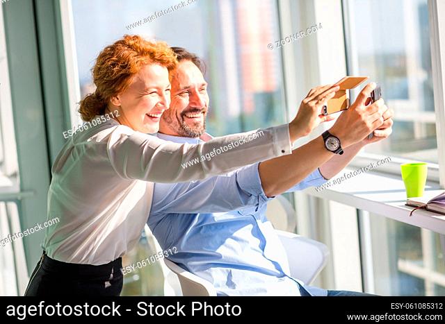 Business people making photos on mobile or smart phone and happy smiling. Workers having break time. Business concept. Freelance concept