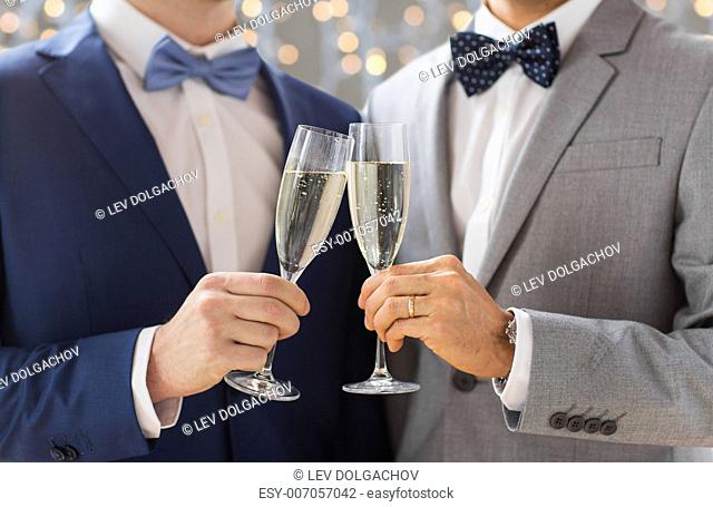 people, celebration, homosexuality, same-sex marriage and love concept - close up of happy married male gay couple drinking sparkling wine on wedding over...