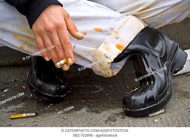 Seattle, Washington, USA: A chef takes a smoke break on the curb outside of a factory that processes food