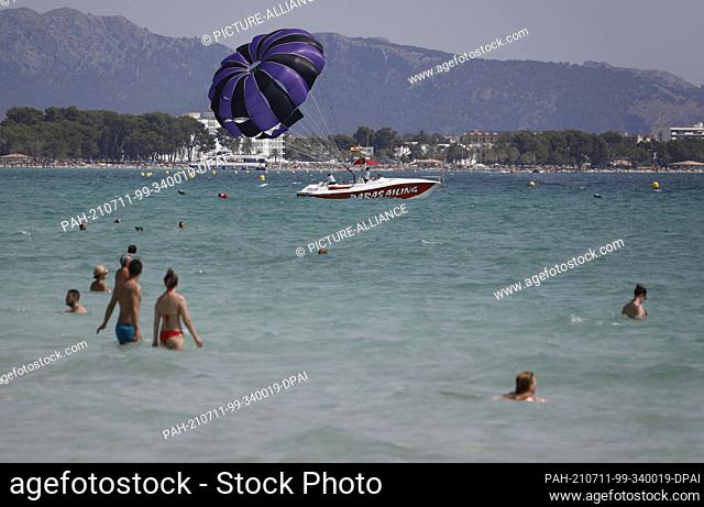 11 July 2021, Spain, -: People bathe in the sea at the beach Playa de Muro in the north of Mallorca. The federal government has declared all of Spain with...