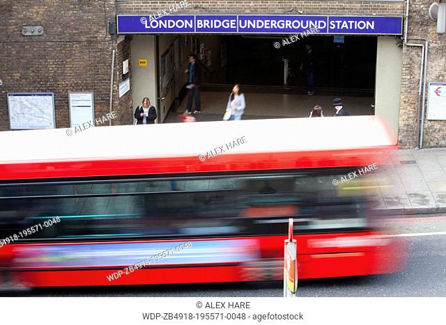 A view of a tradional red London bus as it passes London Bridge underground station