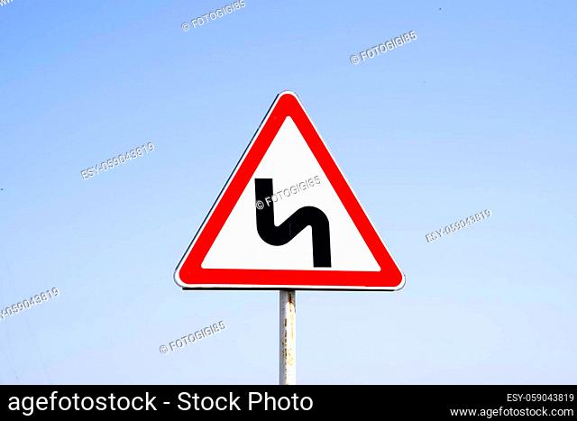 Road sign dangerous turn. Warning a sign