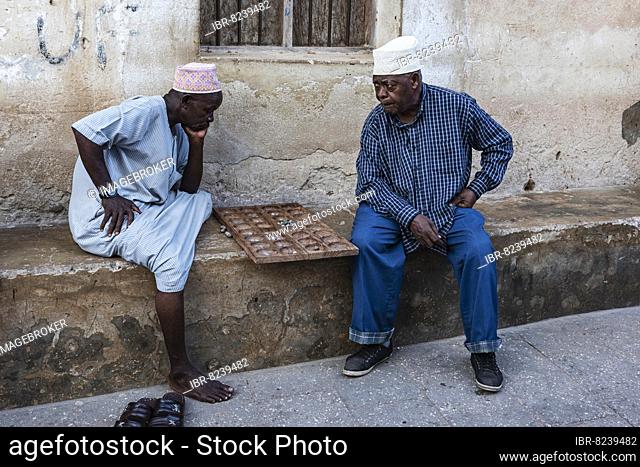 Zwei Männer spielen Bao auf einer Stufe vor dem Haus, typisches Brettspiel Bao Mancala, Stone Town, UNESCO Weltkulturerbe, Altstadt, Sansibar, Unguja, Tansania