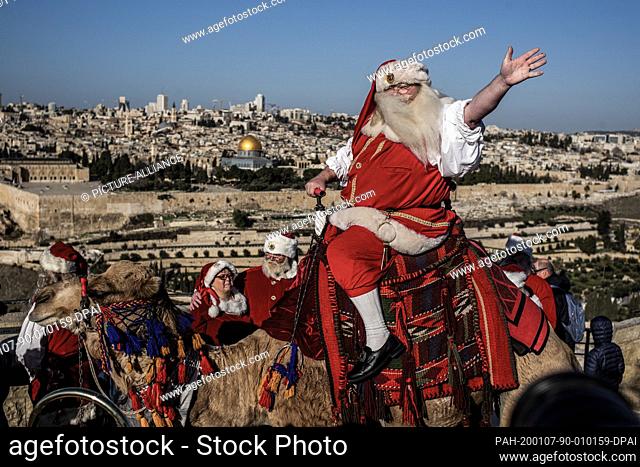 07 January 2020, ---, Jerusalem: A man dressed up as Santa Claus wave as he rides a camel on the Mount of Olives backdropped by Jerusalem's Old City and the...