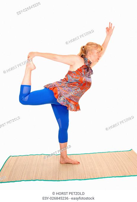 A pretty woman yoga trainer with blond hair standing on one leg and.stretching, isolated for white background.