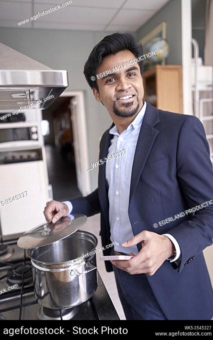 Indian business man cooking with smartphone in hand
