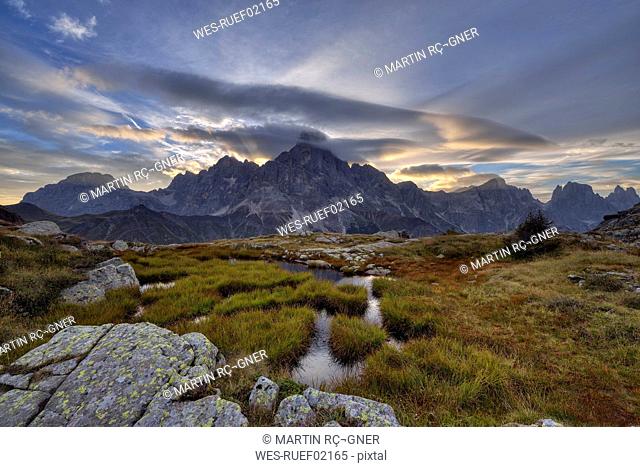 Italy, Dolomites, Passo Rolle, Trentino, Pale di San Martino Mountain group with mountain peak Cimon della Pala with small pond at sunrise