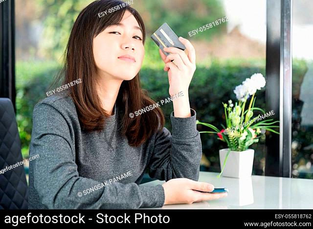 Young woman sitting showing credit card and holding smartphone for online shopping, Online shopping concept
