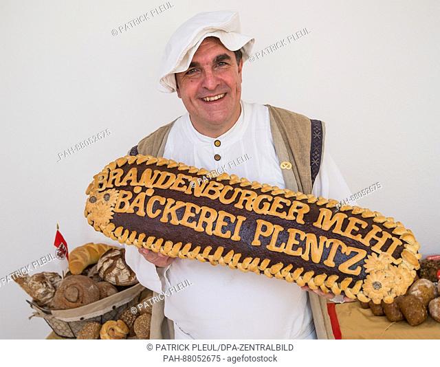 Master baker Karl-Dietmar Plentz holds up a giant bread reading 'Brandenburger Mehl - Baeckerei Plentz' (lit. 'Brandenburg flour - Bakery Plentz') during a...