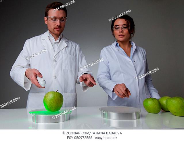 Two scientists in laboratory doing futuristic research experiments with apples, teleportation or cloning concept