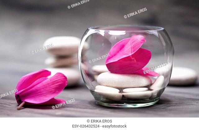 Spa still life with pink orchid, white zen stone and tea candle on dark background