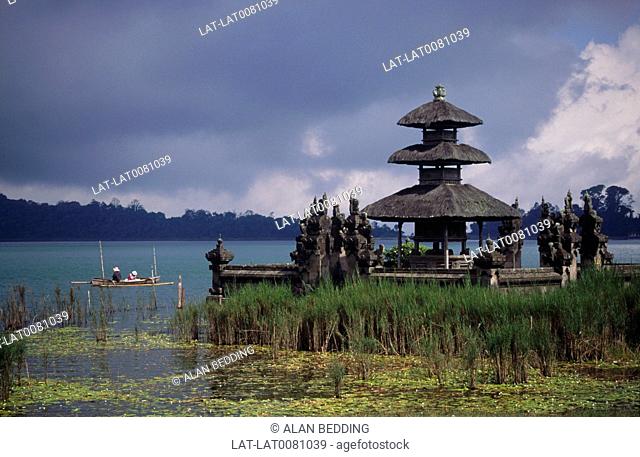 Ulu Danu temple bale/ tower. Thatch. Jetty. Crater lake. Two men in local fishing boat. Reeds