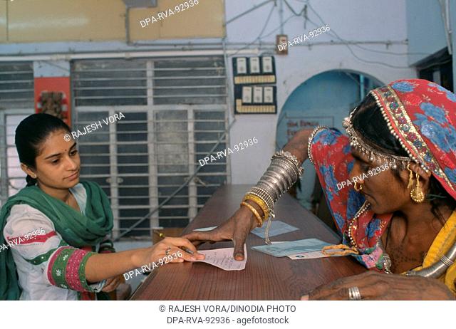 An uneducated rural woman putting a thumb impression in a bank to open her bank account at SEWA Bank , Ahmedabad , India