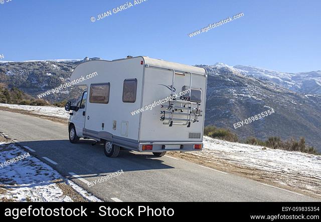Motorhome climbing slowly by mountains pass. Rear outdoor view