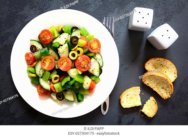 Fresh salad of black and green olives, cherry tomatoes, green bell pepper and cucumber, seasoned with salt, pepper, dried oregano and basil