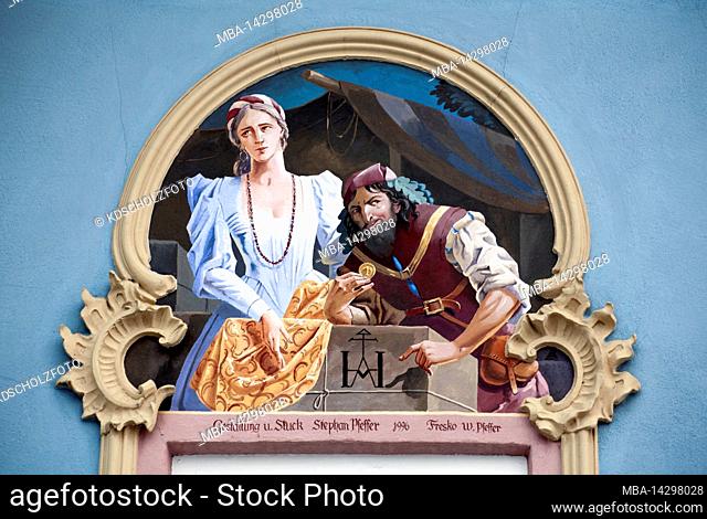 Cloth merchant with cunning look holds a gold coin in his hand, next to it a woman with sad expression, Lüftlmalerei on house facade in Mittenwald