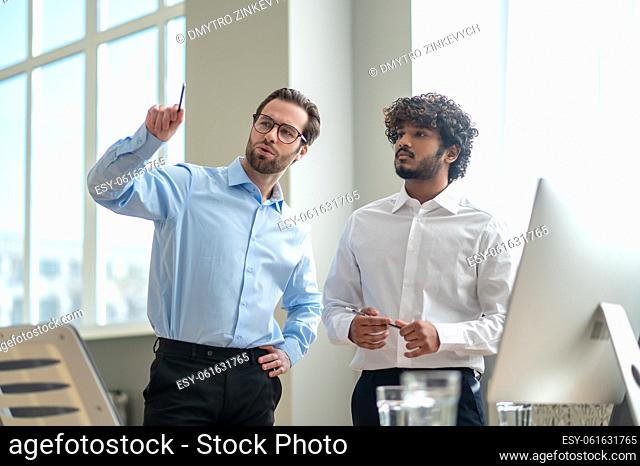 Work on project. Two businessmen looking busy while discussing project in the office