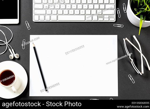 Top view of modern workplace with blank paper sheet. Flat lay black surface with smartphone, notepad and cup of coffee. Top view office workspace and freelance