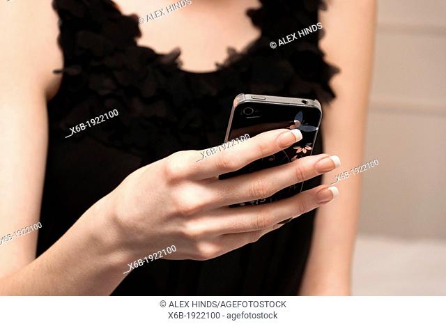 Pretty girl in little black dress texting on mobile phone