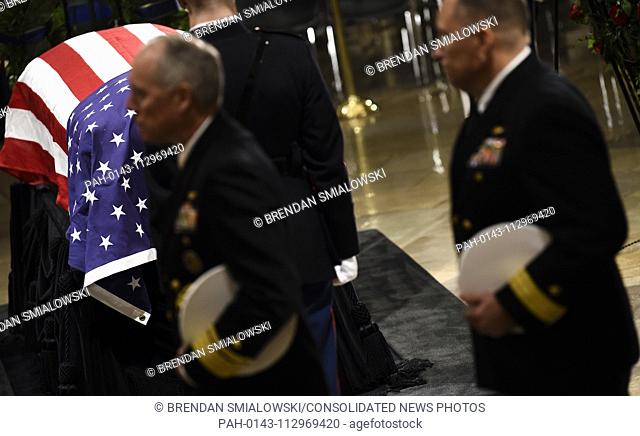 Members of the military pay their respects to President George H.W. Bush as they walk past the casket as he lies in state inside the Rotunda of the US Capitol