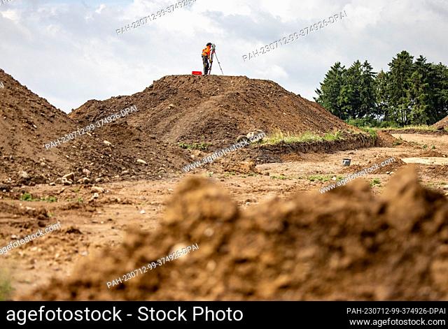 12 July 2023, Schleswig-Holstein, Flintbek: Excavation worker Jörg Matuczak is working on settlement traces from the 4th to 5th century BC from the Migration...