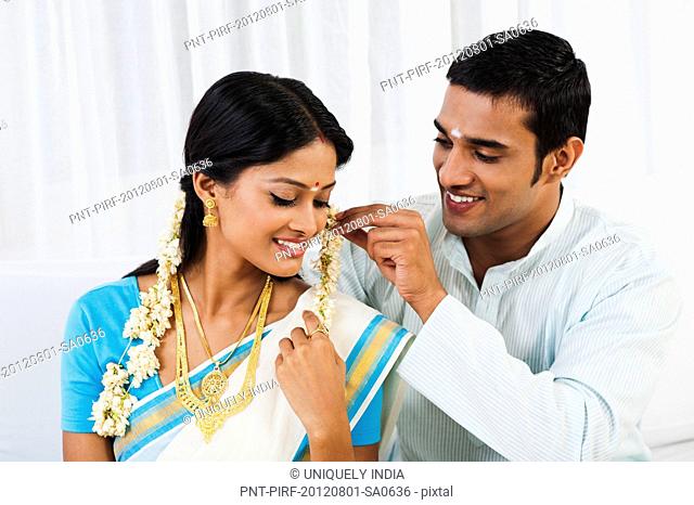 South Indian man putting gajra in his wifes hair