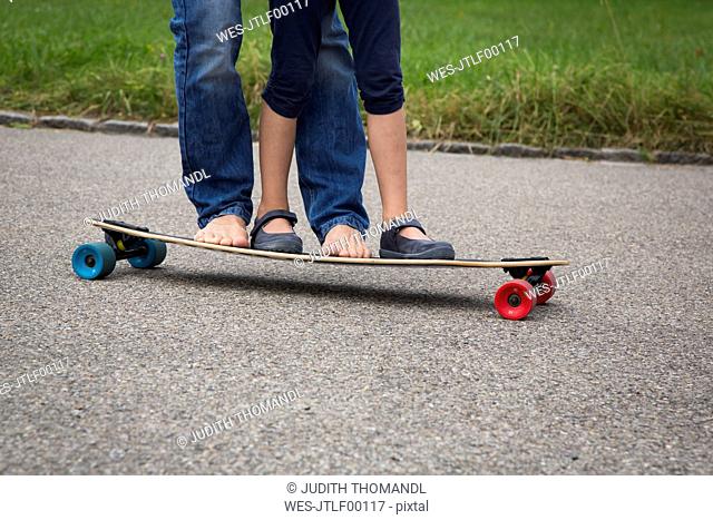 Father and daughter longboarding in garden