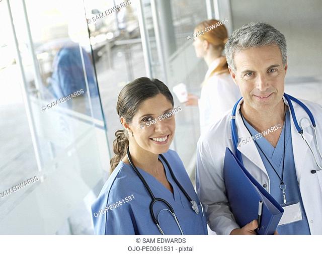 Two hospital workers standing in corridor smiling
