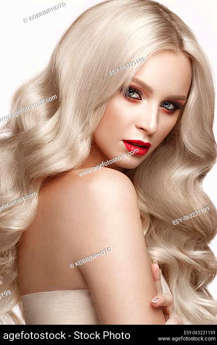 Beautiful blonde in a Hollywood manner with curls, natural makeup and red lips.. Beauty face and hair. Picture taken in the studio