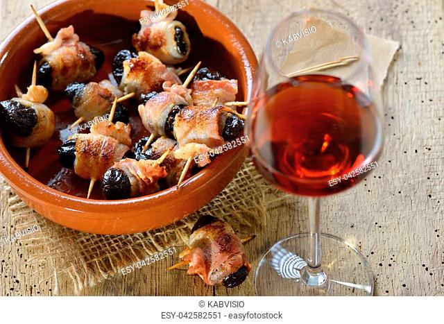Delicious Spanish tapas: Fried prunes wrapped in bacon served with Portuguese port wine