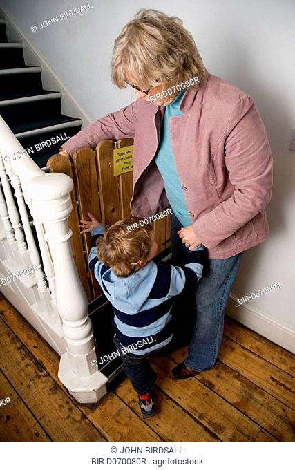 Young boy about to climb stairs at nursery, with his grandmother