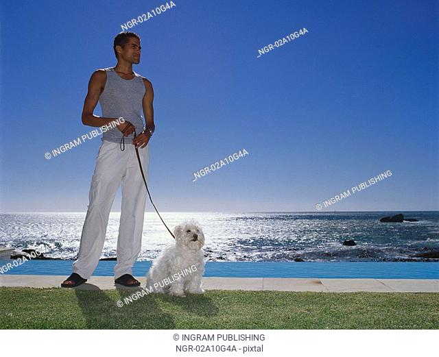 Young man standing holding a dog's leash