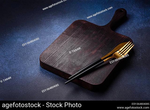 Empty rectangular wooden cutting board on dark concrete background. Cooking at home