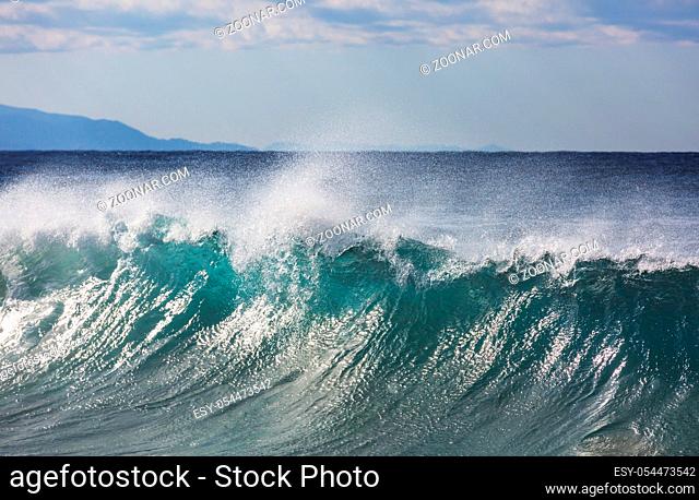 Blue wave on the beach. Blur background and sunlight spots. Peaceful natural background